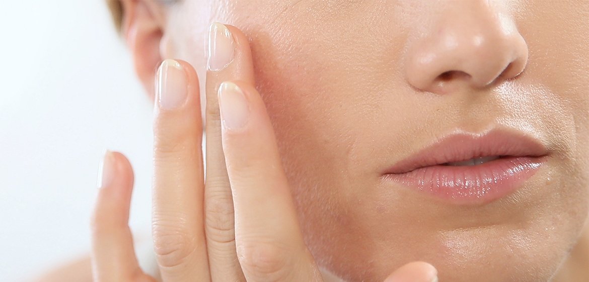 Eine Frau verteilt Make-up auf ihrer Wange - Detailaufnahme